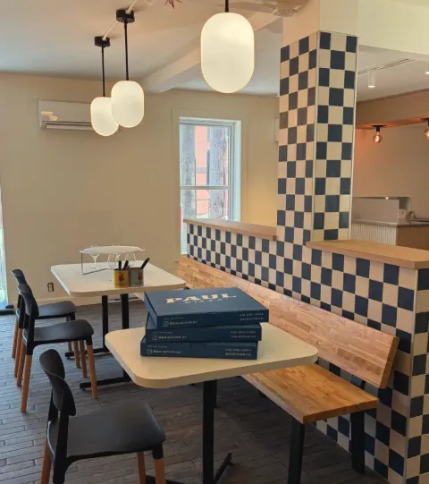 Boîtes de pizza bleues Paul Pizza empilées sur une table